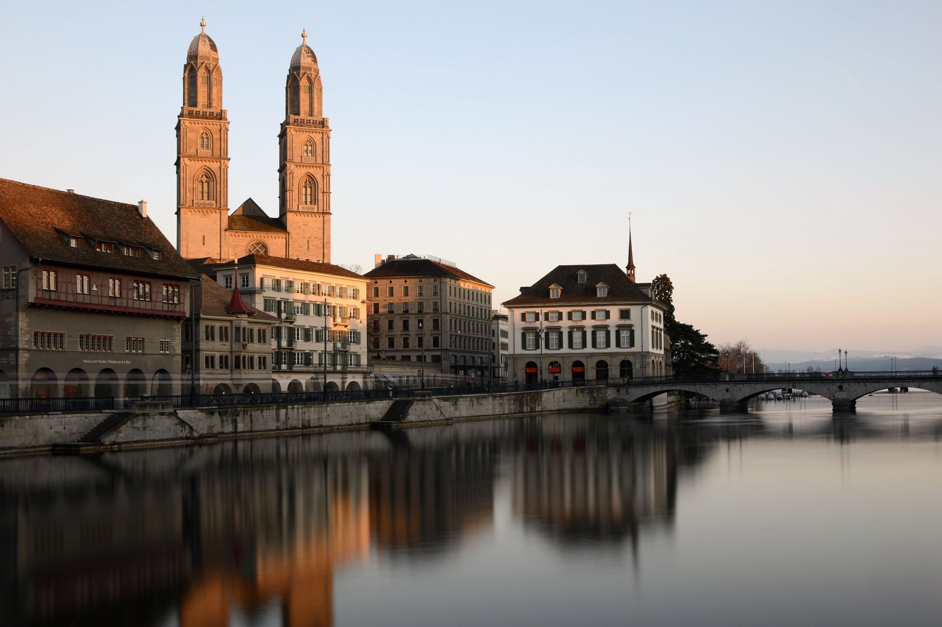cathedral behind building beside body of water with stone bridge
